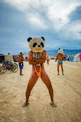 Burning Man burner wearing crazy burning man clothes with giant panda head on Black Rock City playa 